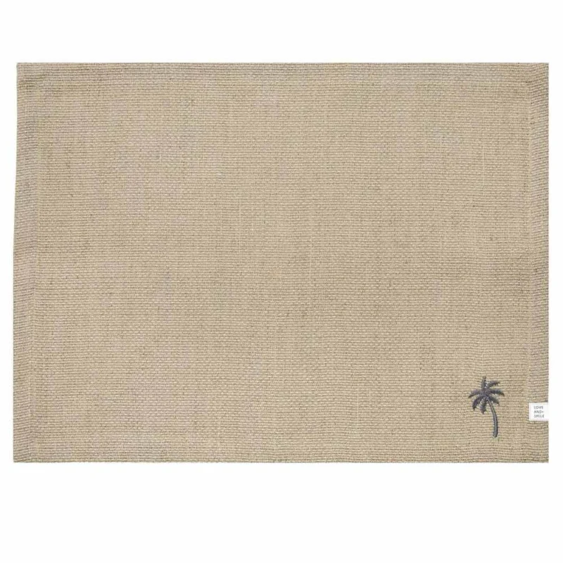 Ein Tischset von Bastion Collections aus beigefarbenem gewebtem Leinen mit einer kleinen gestickten Palme in der unteren rechten Ecke, Maße 48 x 36 cm.