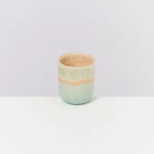 Keramikbecher mit grün-beige Muster auf weißem Hintergrund.