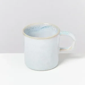 Hellblaue Keramiktasse mit leichtem Farbverlauf auf einer weißen Oberfläche vor grauem Hintergrund.