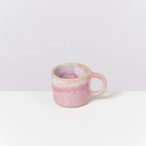 Rosa Tasse mit marmoriertem Design auf einer weißen Oberfläche.