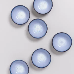 Sechs blaue Schüsseln mit dunklem Rand auf einer weißen Oberfläche angeordnet.
