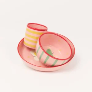 Drei bunte Schüsseln und ein Becher, rosa mit Streifen und fröhlichen Motiven, auf hellem Hintergrund.