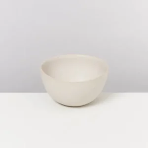 Beige Schüssel auf einem weißen Tisch vor einem hellgrauen Hintergrund.